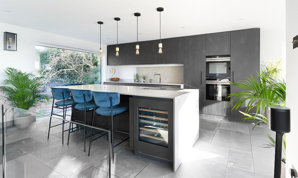 A modern, minimalist one-wall kitchen with gray cabinets and a white countertop central island. The sleek gray cabinetry creates a clean, contemporary look, complemented by the bright white surface of the island, which serves as both a functional workspace and a visual focal point. The simple, streamlined design emphasizes efficiency while maintaining a stylish and sophisticated atmosphere. The overall aesthetic is balanced and inviting, with the central island offering ample room for preparation, seating, or casual gatherings.