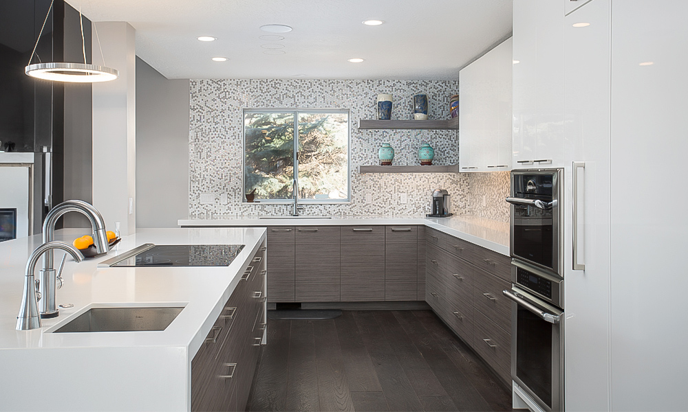 A close-up view of a modern L-shaped kitchen featuring white lacquered cabinets. The image highlights the central island, which is designed with a sleek, minimalist style and complements the glossy finish of the cabinets. The island offers additional counter space, making it both functional and stylish. The bright white cabinetry and island create a clean, contemporary look, perfect for a modern kitchen setting.