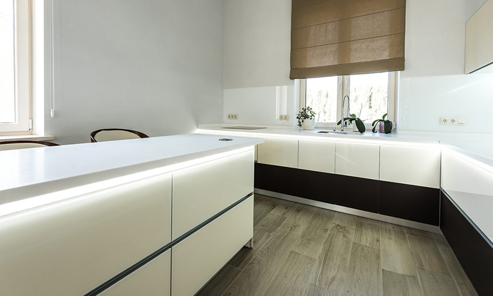 Close-up view of a modern L-shaped kitchen featuring white lacquered cabinets and a central island, highlighting the sleek design and contemporary details.
