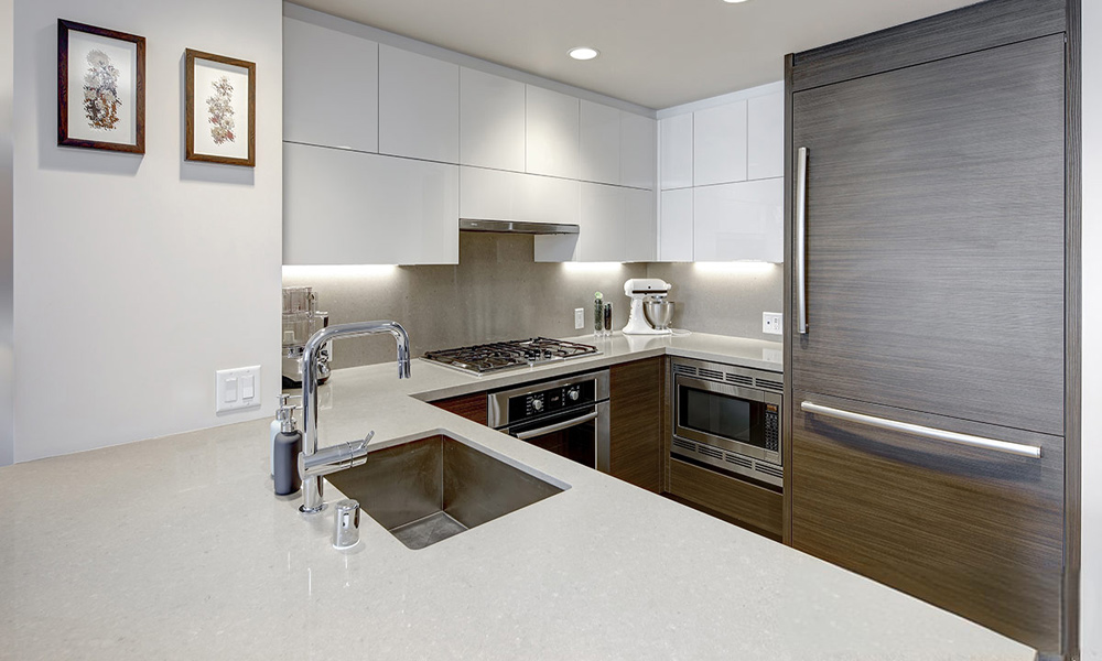 A modern U-shaped kitchen featuring wood veneer base cabinets, white lacquered upper cabinets, and a marble central island, combining natural warmth with sleek contemporary elegance.