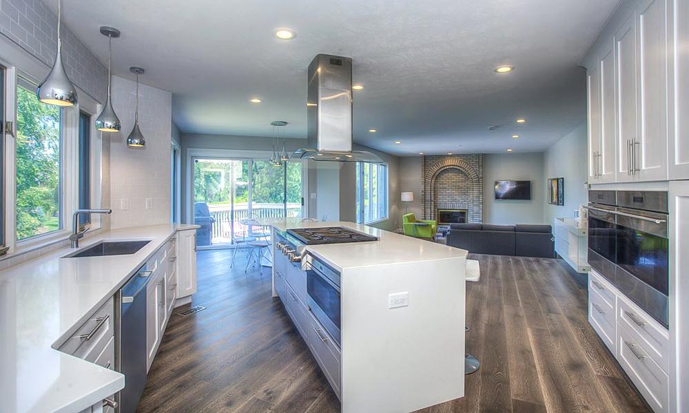 A one-wall kitchen with glossy white lacquered cabinetry and a central island. The smooth, shiny finish of the cabinets complements the bright, modern aesthetic, while the island provides additional counter space and serves as a stylish focal point in the kitchen.