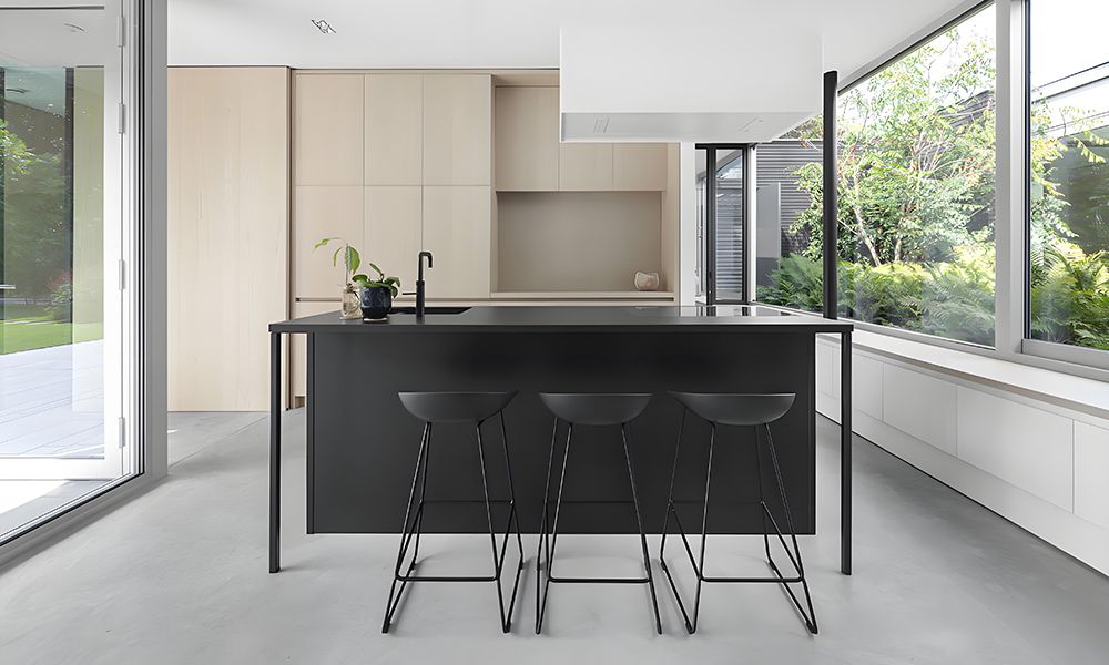 A one-wall kitchen featuring wood veneer cabinets and a bold black central island. The warm tones of the wood cabinets contrast beautifully with the sleek black island, creating a stylish and contemporary look, while the layout ensures a functional, efficient space.
