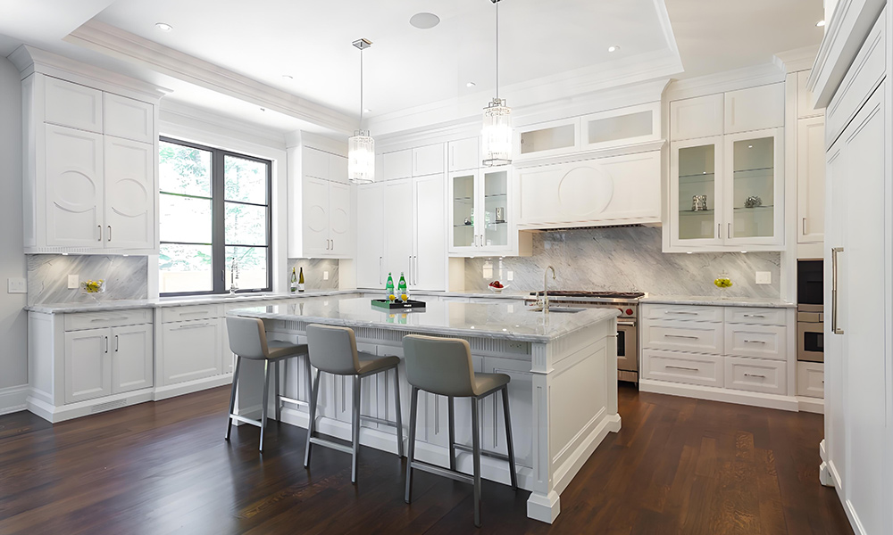 A modern kitchen with white cabinetry and a central island. The sleek, minimalist design highlights the clean white tones of the cabinets, while the island adds a functional and stylish centerpiece to the space, enhancing the open, bright atmosphere.