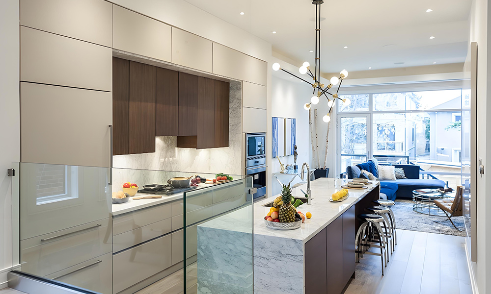 A sleek kitchen featuring glossy white cabinets and a central island. The high-gloss finish of the white cabinetry enhances the bright, modern aesthetic, while the island adds both functionality and a contemporary focal point to the space.